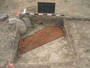 Unit in Area 2, just outside a house platform, highlighting the soil stain that proved to be a trench dug into the soak stone (volcanic stone layer) by a former inhabitant of the house. Arrow points north.