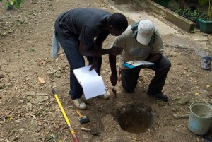 Recording Munsell sediment colors in a shovel test pit in Area 2. Photographed by Hayden Bassett, June 2014.